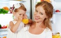 Happy family mother and baby daughter drinking orange juice in Royalty Free Stock Photo