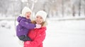 Happy family mother and baby girl daughter playing and laughing in winter snow Royalty Free Stock Photo