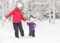 Happy family mother and baby girl daughter run, walk and playing in winter snow Royalty Free Stock Photo