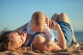 Happy family, mother and baby lies on the sunset sea beach. Parent with children on summer vacations Royalty Free Stock Photo