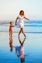 Happy family - mother, baby run on sunset beach Royalty Free Stock Photo