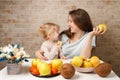 Happy family mother and child baby daughter with healthy food fruits on the kitchen Royalty Free Stock Photo