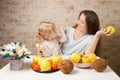 Happy family mother and child baby daughter with healthy food fruits on the kitchen indoor Royalty Free Stock Photo