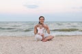 Happy family mother and child daughter doing yoga, meditate in lotus position on beach at sunset Royalty Free Stock Photo