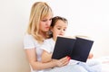 Happy family mother child daughter little girl reading a book by the window Royalty Free Stock Photo