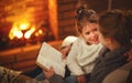 happy family mother and child daughter read book on winter evening near fireplace. Royalty Free Stock Photo