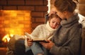 happy family mother and child daughter read book on winter evening near fireplace Royalty Free Stock Photo