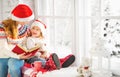 Happy family mother and child daughter reading book on winter wi Royalty Free Stock Photo
