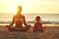 Happy family mother and child doing yoga, meditate in lotus position on beach . Royalty Free Stock Photo