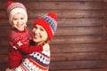 Happy family mother and child girl hugs at wooden background