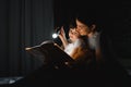 Happy family mother and child son reading a book with a flashlight. Family before going to bed mother reads to her child son book Royalty Free Stock Photo