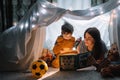 Happy family mother and child son reading a book with a flashlight in a tent at home. family concept Royalty Free Stock Photo