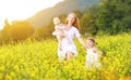 happy family, mother and children little daughter and baby running on meadow with yellow flowers