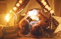 Happy family mother and children reading a book in tent at hom Royalty Free Stock Photo