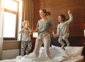 Happy family mother and children son and daughter jumping, laughing, playing in bed