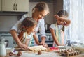 Happy family mother and children twins bake kneading dough in Royalty Free Stock Photo
