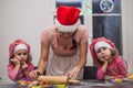 Happy family mother and children twins daughter bake kneading dough in the kitchen, bored twin girls watching mother