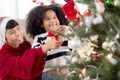 Happy family with mother and daughter decorating ornament on Christmas tree together at home, thanksgiving eve. Royalty Free Stock Photo