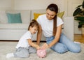 Happy Family Mother And Daughter Putting Coins In Piggy Bank At Home Royalty Free Stock Photo