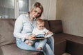 Happy family mother and daughter read a book in the evening at home sitting on the couch Royalty Free Stock Photo