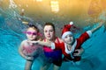 Happy family - mother, daughter and son in a red suit Santa Claus swim underwater in the pool, looking at me and smiling. Portrait Royalty Free Stock Photo