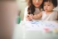 Happy family mother and daughter together paint. Asian woman helps her child girl. Royalty Free Stock Photo