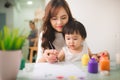 Happy family mother and daughter together paint. Asian woman helps her child girl. Royalty Free Stock Photo