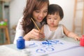 Happy family mother and daughter together paint. Asian woman helps her child girl. Royalty Free Stock Photo