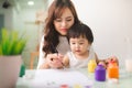 Happy family mother and daughter together paint. Asian woman helps her child girl. Royalty Free Stock Photo