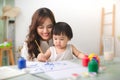 Happy family mother and daughter together paint. Asian woman helps her child girl. Royalty Free Stock Photo