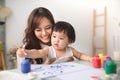 Happy family mother and daughter together paint. Asian woman helps her child girl. Royalty Free Stock Photo