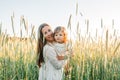 Happy family, mother in a dress with a cute little baby on a golden wheat field at sunset. summer day Royalty Free Stock Photo