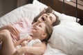 Happy family mother embracing kid daughter laughing lying on bed Royalty Free Stock Photo