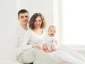 Happy family mother and father with baby home in white room near window Royalty Free Stock Photo