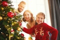 Happy family mother, father and child daughter decorate Christmas tree