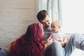 happy family of mother, father and child son playing and cuddling at home on floor near a big window. Royalty Free Stock Photo