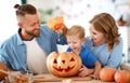 Happy family mother father and child son prepare for Halloween decorate home with pumpkins and laughing, play and scare with