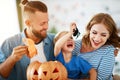 Happy family mother father and child son prepare for Halloween decorate home with pumpkins and laughing, play and scare with