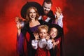 Happy family mother father and children in costumes and makeup on  Halloween on dark red background Royalty Free Stock Photo