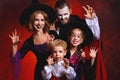 Happy family mother father and children in costumes and makeup on  Halloween on dark red background Royalty Free Stock Photo