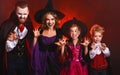 Happy family mother father and children in costumes and makeup on  Halloween on dark red background Royalty Free Stock Photo