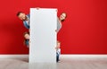 Happy family mother father and children daughter and son  near an   red wall with a white blank poster Royalty Free Stock Photo