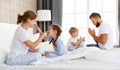 Happy family mother, father and children laughing, playing, fights pillows and jumping in bed   at home Royalty Free Stock Photo