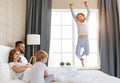 Happy family mother, father and children laughing, playing, fights pillows and jumping in bed   at home Royalty Free Stock Photo