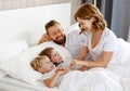 Happy family mother, father and children laughing, playing, fights pillows and jumping in bed   at home Royalty Free Stock Photo