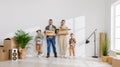 Happy family mother father and children move to new apartment and stand in a row with boxes in their hands against an empty wall Royalty Free Stock Photo