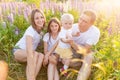 Happy family mother father embracing kids outdoor. Woman man baby child and teenage girl sitting on summer field with Royalty Free Stock Photo