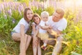 Happy family mother father embracing kids outdoor. Woman man baby child and teenage girl sitting on summer field with Royalty Free Stock Photo