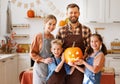 Happy family mother, father and kids smiling at camera make jack-o-lantern from pumpkin, getting ready for halloween Royalty Free Stock Photo