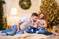 Happy family of mother, father kissing and hugging little baby girl near Christmas tree. Royalty Free Stock Photo